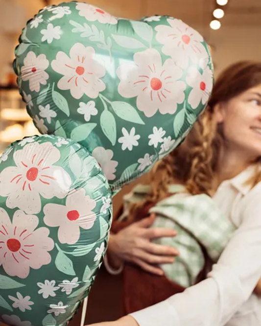Floral heart-shaped balloons held by a person with a blurred background