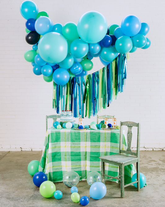Decorative setup with balloons and tassels on a table with a green checkered tablecloth.
