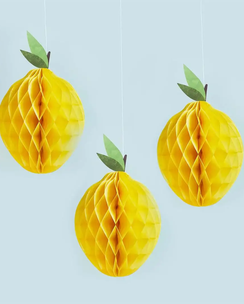 Three yellow honeycomb lemon decorations with green leaves on a light blue background