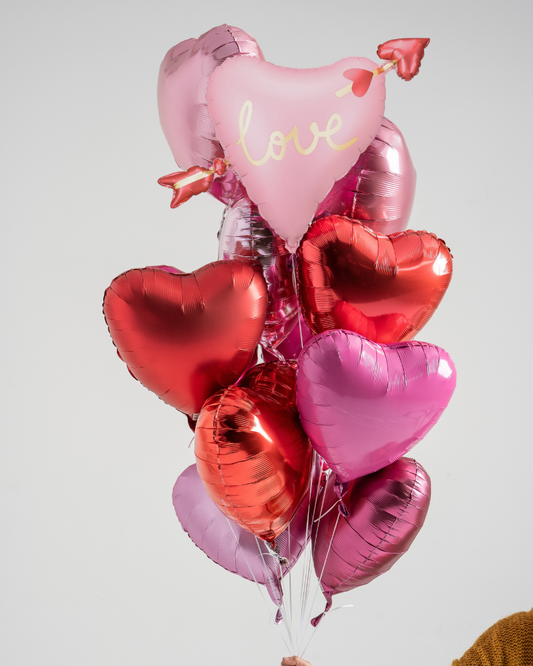 Heart-shaped balloons with 'love' text on a light gray background