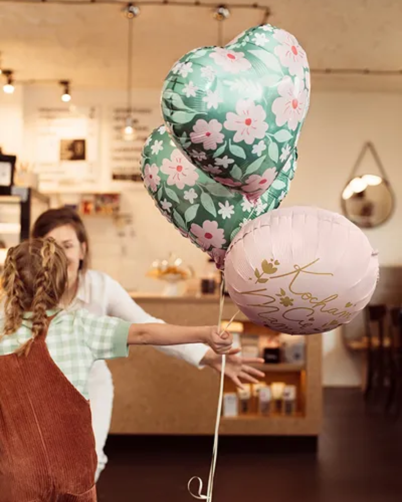 Two people holding heart-shaped balloons in a store setting
