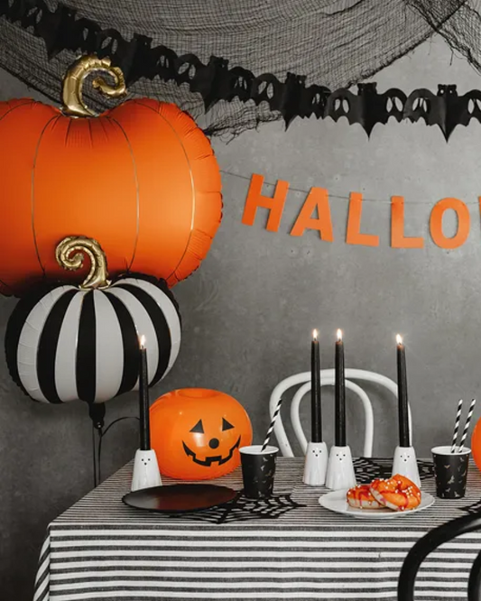 Halloween-themed table setting with balloons, candles, and decorations.