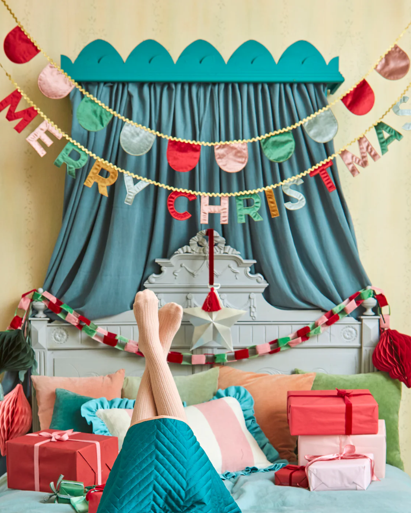 Decorated room with Christmas decorations, including a 'Merry Christmas' banner and presents.
