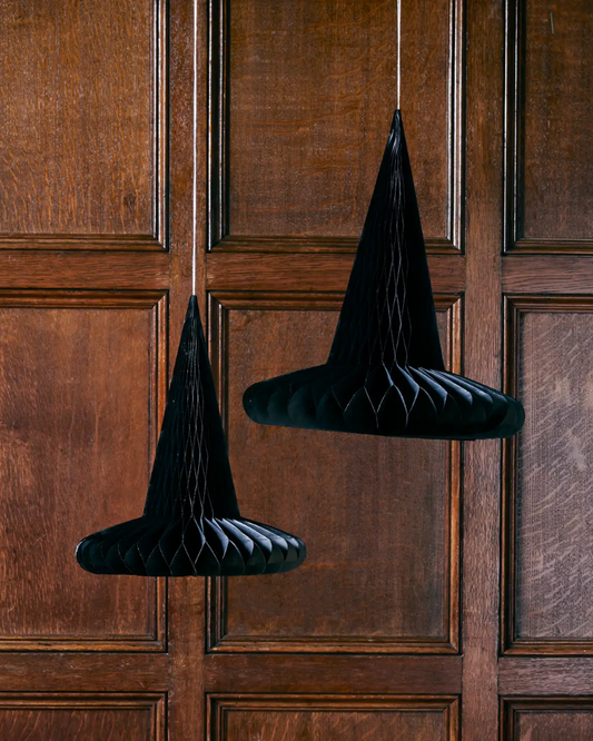 Two black witch hats hanging on a wooden door