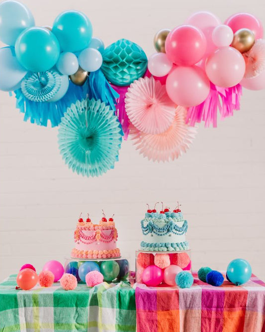 Colourful baby shower party setup with balloons, cake, and decorations on a table.
