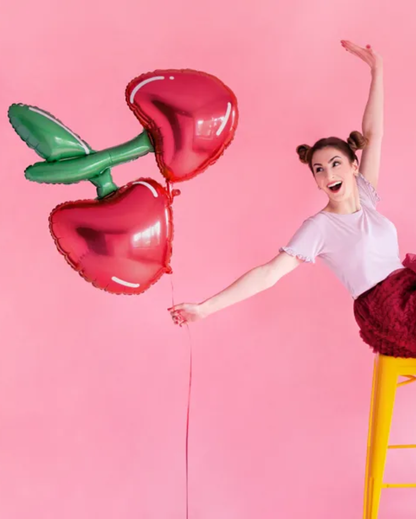 Woman holding a large red heart-shaped balloon against a pink background