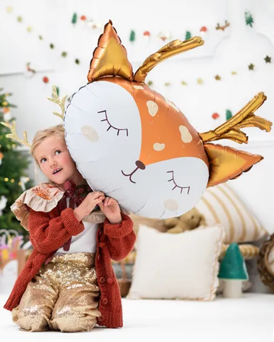 Child holding a reindeer-shaped balloon in a festive setting with Christmas decorations.
