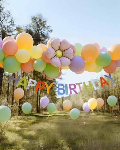 Colorful 'Happy Birthday' banner in a park setting