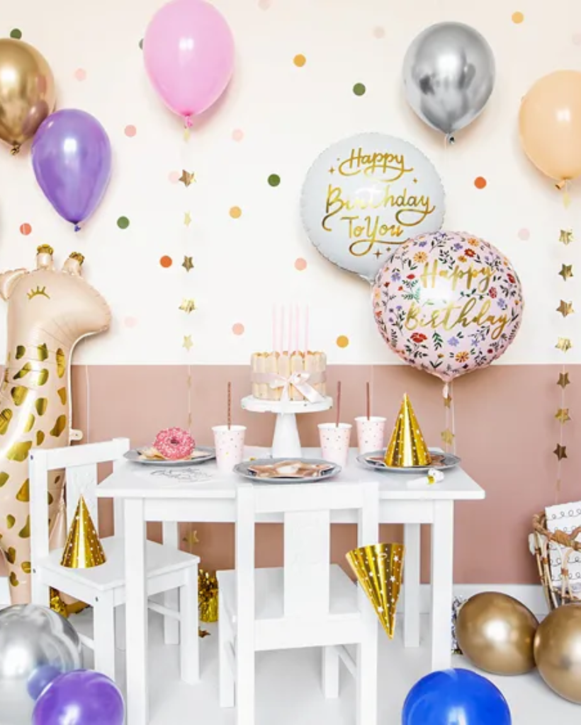 Children's birthday party setup with balloons, cake, and tableware.