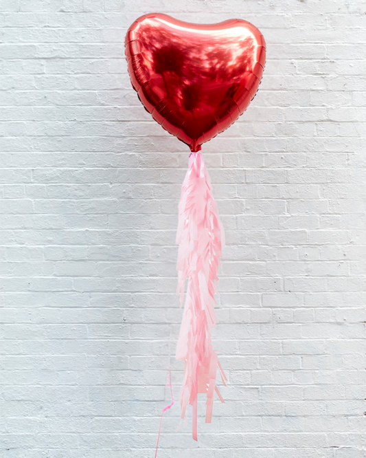 A red jumbo heart-shaped foil balloon with a fringe tail