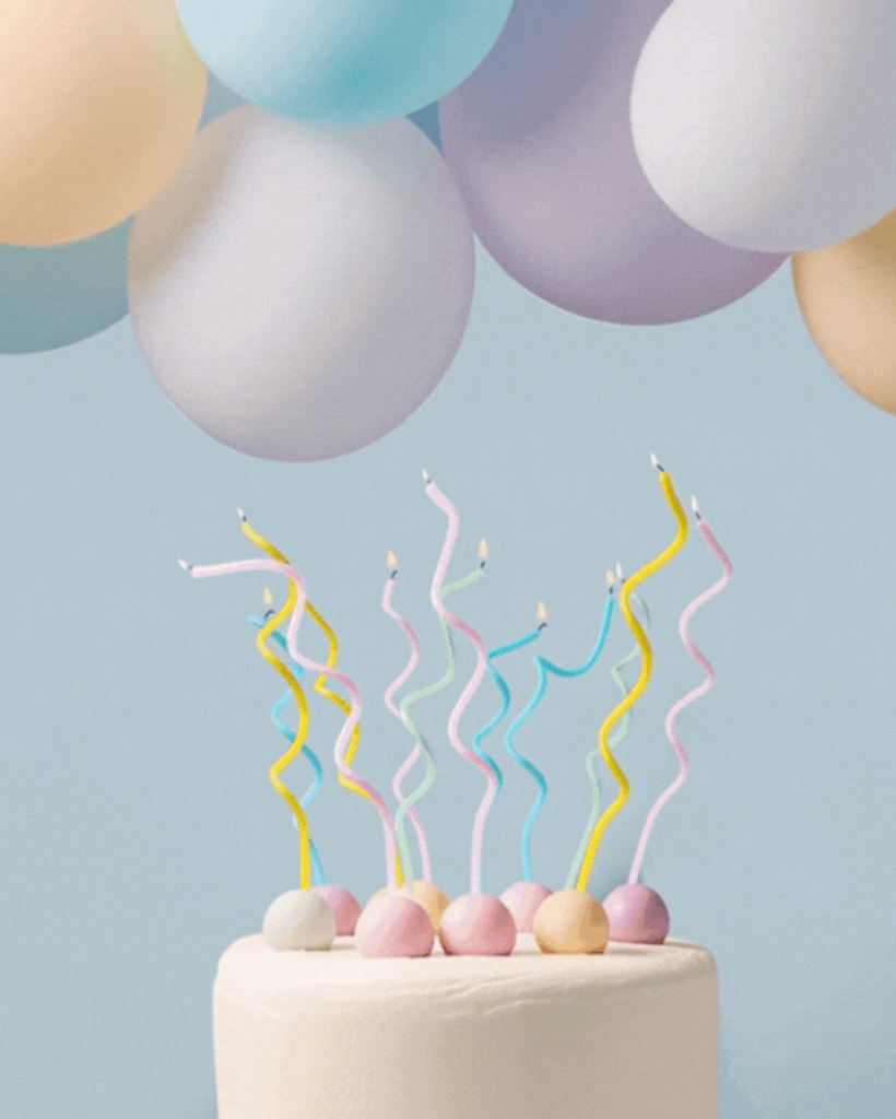 Pastel-colored wavy candles on a cake against a light blue background