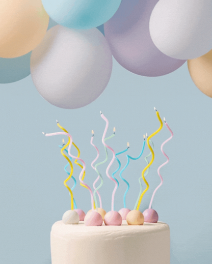 Pastel-colored wavy candles on a cake against a light blue background
