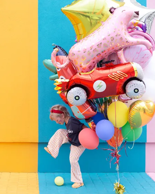 Child playing with colorful balloons against a bright yellow and blue background