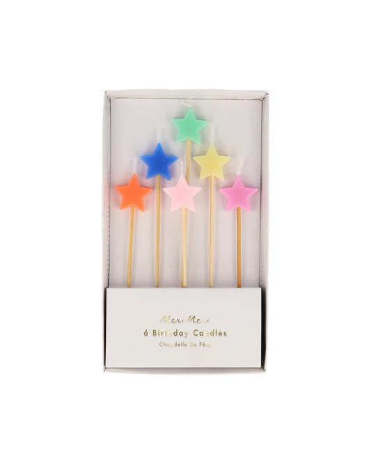 Set of colorful star-shaped birthday candles in a box on a white background