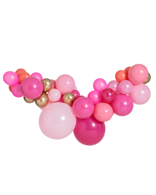 A curved balloon garland featuring a variety of pink shades along with some gold and coral balloons, arranged in a gradient pattern.