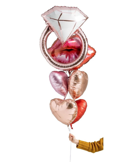 A bouquet of foil balloons filled with helium, including shapes of a diamond ring, lips, and hearts, all in a multicolored design.
