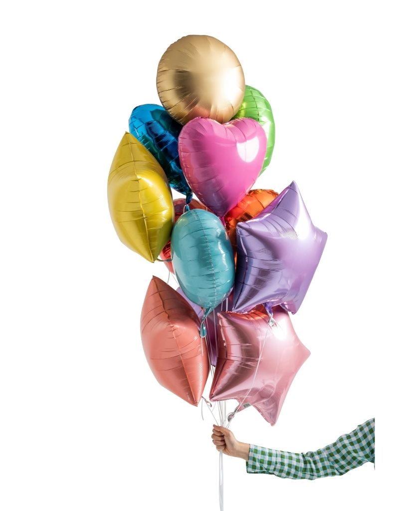 A bouquet of multicolored balloons including gold, pink, blue, green, and purple balloons, held by a person.