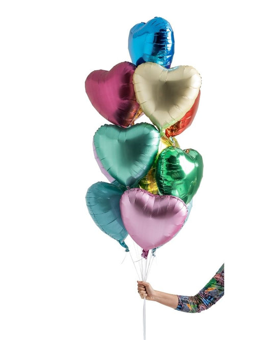 A bouquet of multicolored heart-shaped foil balloons being held by a person.