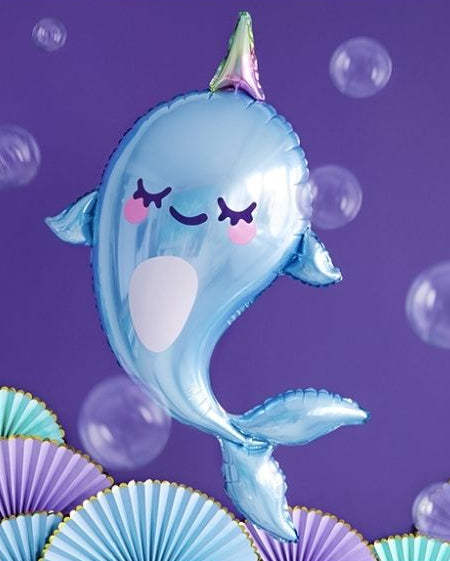 Blue narwhal-shaped balloon against a purple background with bubbles