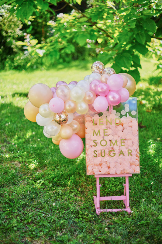 pink blossom party welcome sign with balloon garland attached.